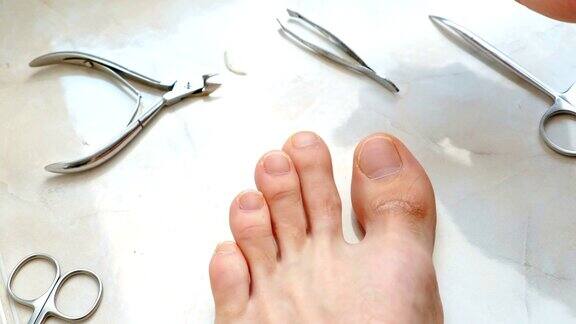 用剪子剪脚趾甲的男人男性剪脚趾甲脚和脚趾特写前视图
