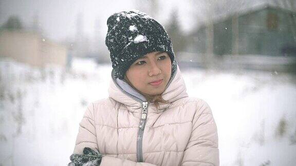 亚洲女孩在寒冷的冬天从雪中颤抖慢动作