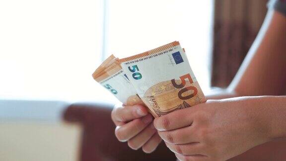 女人的手在数欧元钞票和计算器的成本