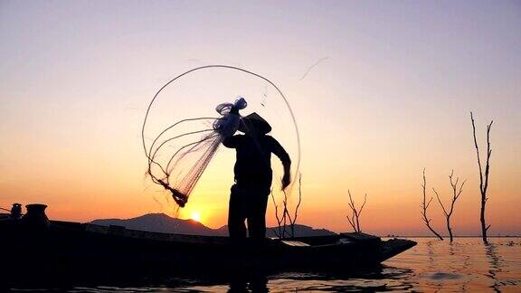 高清慢镜头:泰国日落时分渔民在长尾船上捕鱼