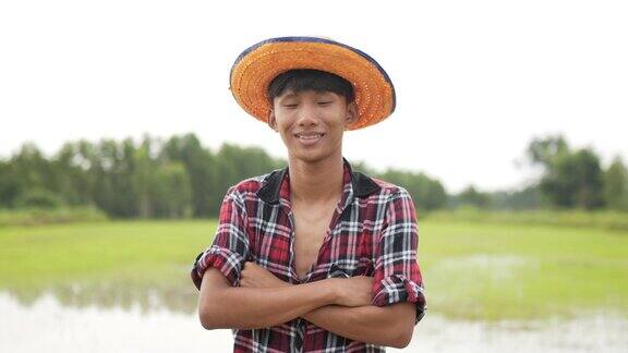 年轻的农民站在稻田里双臂交叉