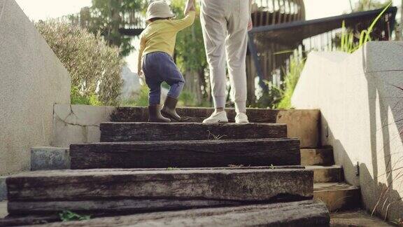 后视图:年轻的亚洲母亲和儿子一起走在楼梯上