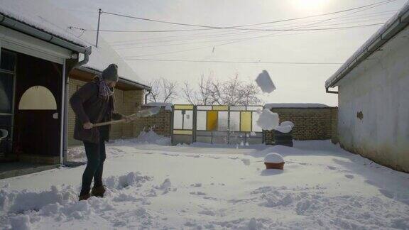 男人正在院子里铲新雪