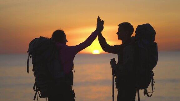 男人和女人背着背包站在美丽的海景日落
