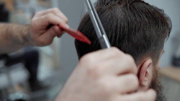 理发师在理发店用剪刀剪头发的特写理发师的手在工作过程中理发师理发有吸引力的胡子男子在理发店理发师在起作用美容沙龙