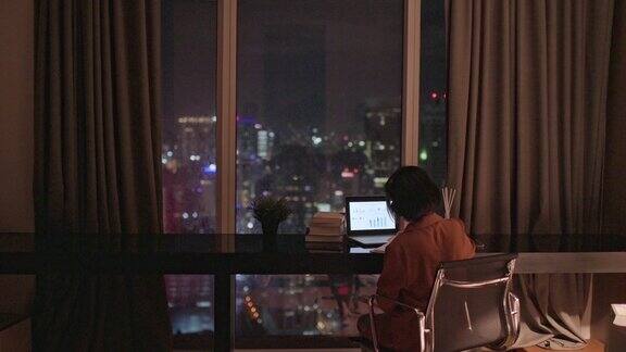 亚洲华人美丽的女人使用笔记本电脑工作在家自习室书写耳机