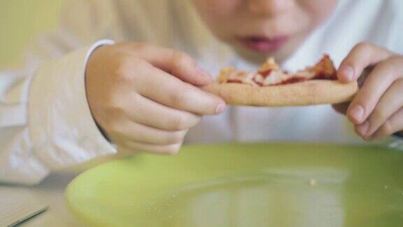 戴眼镜的学童在餐桌上吃新鲜的披萨