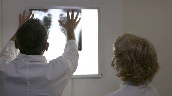 佩戴防护口罩的医生的后视图和观察x光透视镜