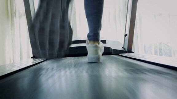 健身女孩在跑步机上跑步近距离的女人与肌肉腿在健身房