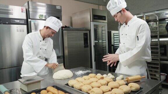 在商业面包房的厨房里男厨师长和年轻男厨师长协助一起揉面称重准备做面包和小圆面包的面团