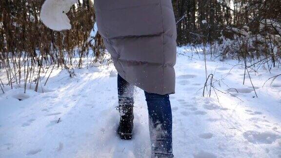 一个无法辨认的女人穿着冬装跑过白雪覆盖的森林踩着厚厚的积雪女性远足者在寒冷的冬天慢跑的腿上的后视图女孩去户外慢镜头