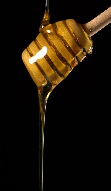(实时和垂直)蜂蜜从一个木制的蜂蜜勺流动