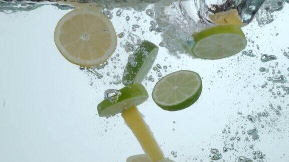 柠檬片和酸橙片在慢镜头中溅入水中