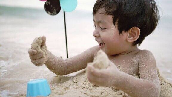 亚洲母亲和她的儿子在沙滩上玩沙子