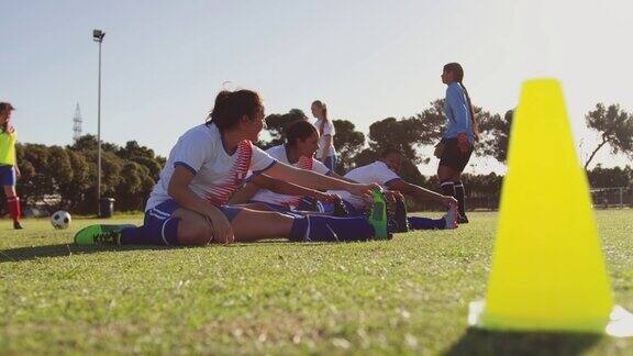 女足球运动员在足球场上训练前伸展4k
