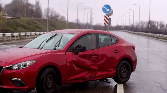 下雨的时候在路上发生了车祸一辆被损坏的红色汽车停在空旷的路上