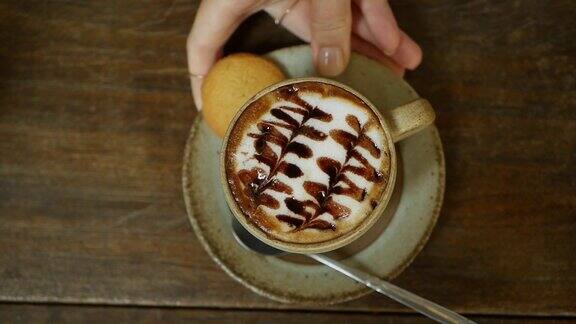 咖啡师在桌子上放了一杯拉花咖啡手把一杯加牛奶的咖啡放在咖啡馆咖啡休息特写镜头