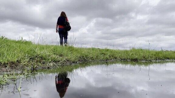 看风景背影一个女人走过水然后站在秋天的云彩前系列的一部分