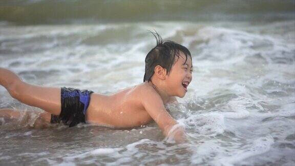 慢镜头拍摄的亚洲男孩在沙滩上享受和玩海和沙子
