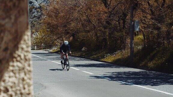 一名职业自行车手在高山背景下的道路上骑着高速自行车