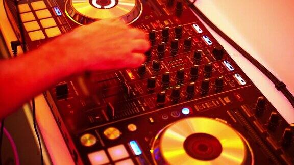 特写的DJ的双手扭动着按下DJ遥控器上不同的按钮颜色和轻音乐在俱乐部里与dj派对