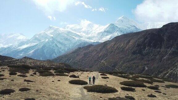 一对夫妇在尼泊尔喜马拉雅山Annapurna马戏团徒步旅行的Manang山谷在Annapurna链和Gangapurna的景色干燥和荒凉的景观白雪覆盖着高耸的山峰