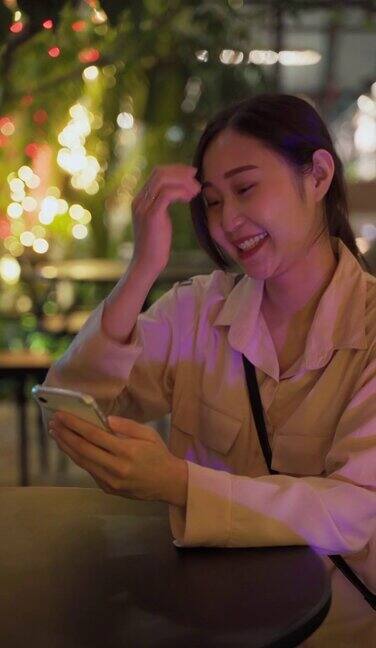 年轻的亚洲女性使用手机工作到深夜