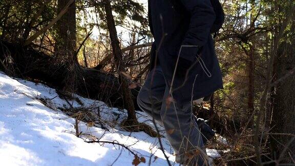 在阳光明媚的日子里年轻男性游客在雪坡上徒步旅行快乐的徒步者在阳光的背景下爬上雪山特写慢动作