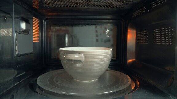 那个人把一碗食物放进微波炉加热在相机
