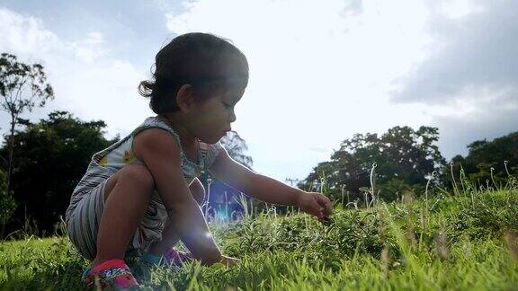 亚洲小女孩训练走路坐在绿色的草地上玩耍母亲节慢镜头