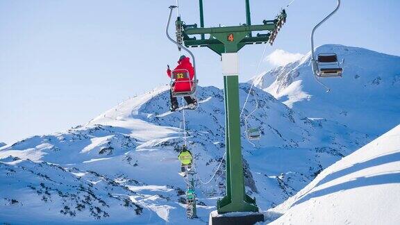 滑雪者在乘坐滑雪缆车前往雪山山顶时用智能手机拍照