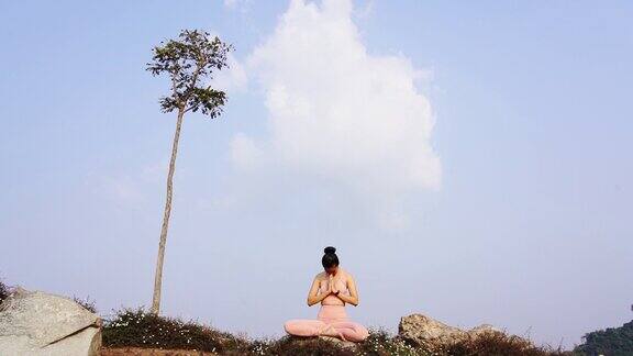 快乐女人瑜伽姿势平衡身体冥想在自然蓝天山脉的背景
