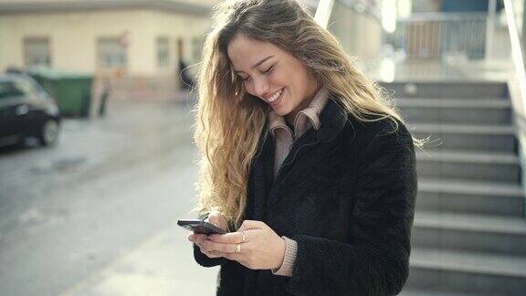 年轻美丽的西班牙女子在街上用智能手机微笑自信