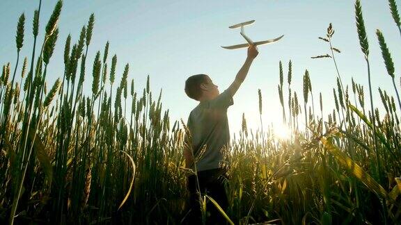 日落时分一个男孩在田野里玩飞机
