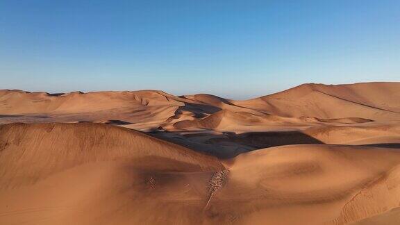 镜头移向巨大的红色沙丘和蓝色天空的地平线