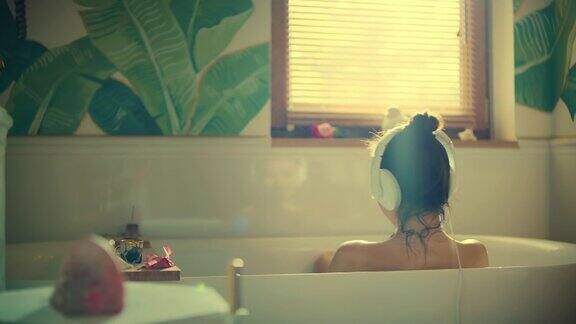 一个年轻的女人正在她的浴室里郁郁葱葱的绿色花园里泡澡吹灭泡沫