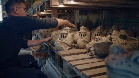 陶艺家在陶瓷作坊里把青蛙和蜗牛雕塑放在桌子上