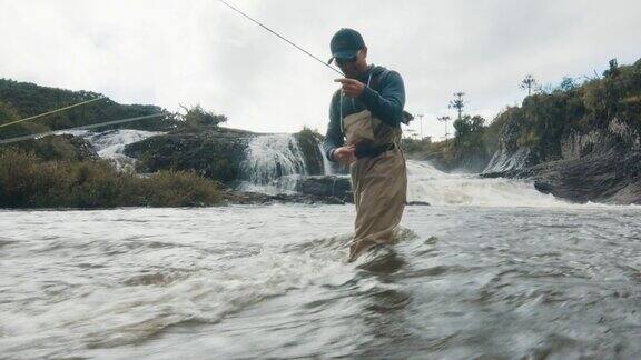 垂钓者钓到小鱼穿着水靴的渔夫在湍急浑浊的河水中钓到的鱼不多