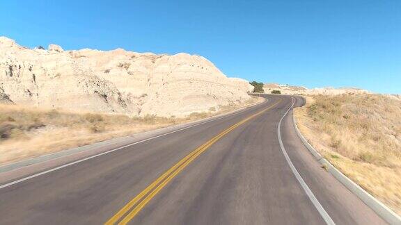 FPV:驾驶在空旷的道路上蜿蜒穿过广阔的Badlands山沙漠