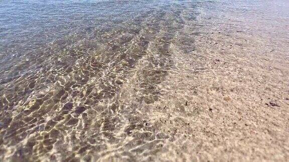 海面特写慢镜头阳光照在海面上水面上泛起小涟漪沙质海底起腐蚀作用沙质带滩海浪拍打着海滩
