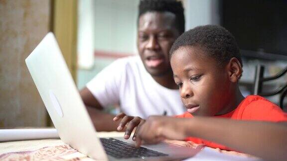 父亲和儿子在家里用笔记本电脑在线学习