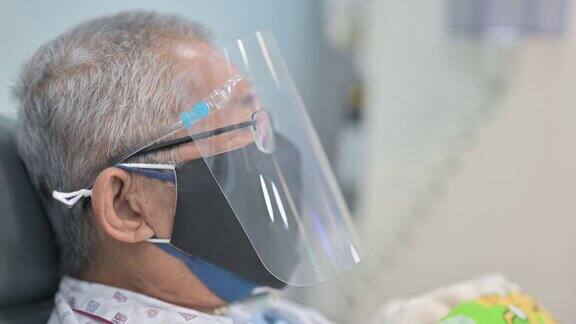亚洲华人老人坐在椅子上戴着面罩正在医院接受透析治疗
