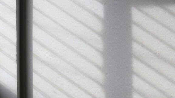 时间流逝:阳光的背景透过窗户照在白色的混凝土墙上