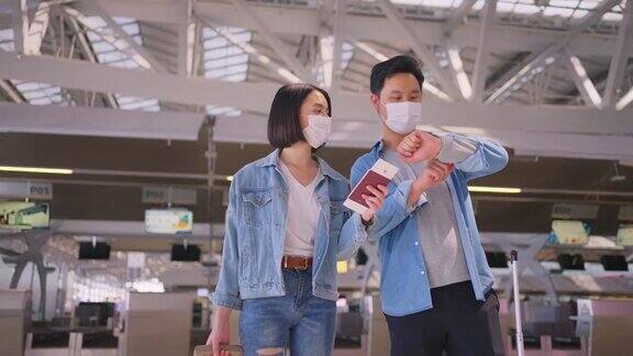 新冠肺炎疫情期间为了预防新冠肺炎感染戴口罩的男女旅客在机场航站楼走向登机口航空运输的新常态生活理念