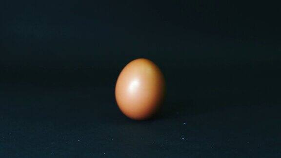 鸡蛋在黑色的背景上旋转脱离了框架一个带壳的鸡蛋在黑暗的桌子上旋转的慢镜头特写4k分辨率