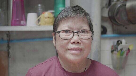 快乐的亚洲老女人看着厨房里的摄像头