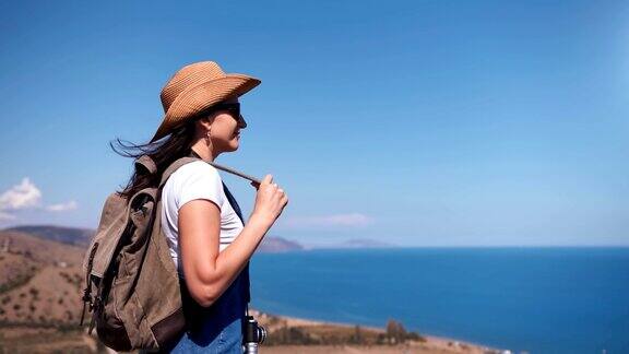 潮人放松的背包女子站在山顶欣赏惊人的海景