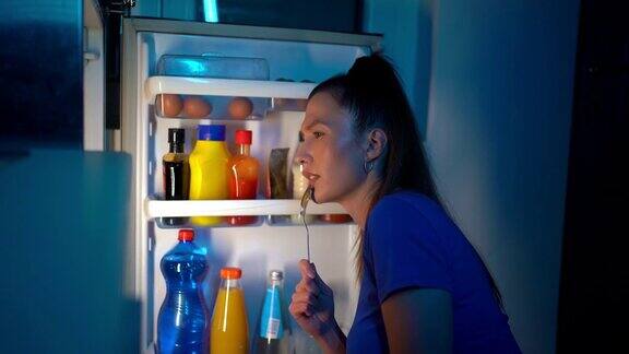 一个女人在晚上往冰箱里看