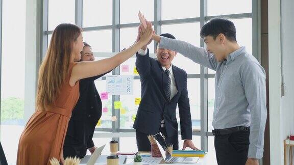 快乐亚洲的专业商务办公室团队在办公室一起击掌庆祝亚洲的同事们集体庆祝企业的成功从事团结团队合作伙伴的理念