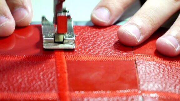 工厂生产真皮制品在缝纫机上缝合红色皮革